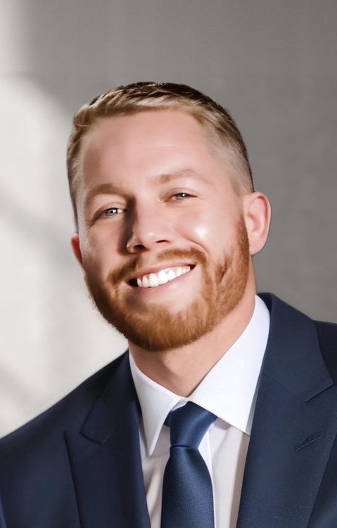 Ashton Harris in a navy suit, smiling