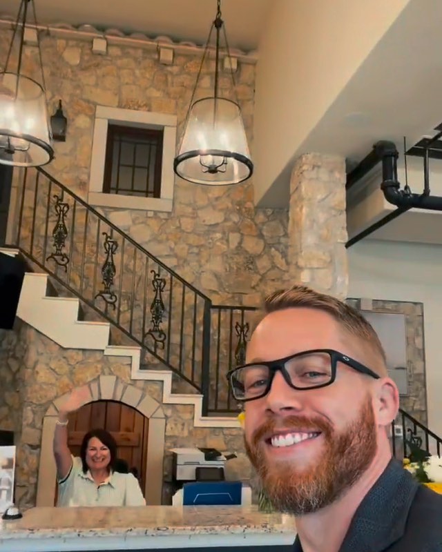 Me smiling in the title company's lobby on closing day while the receptionist waves behind me