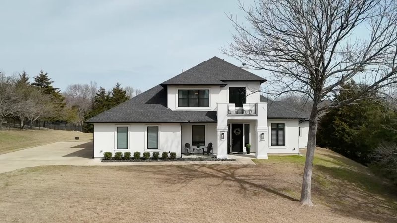 The front of 4571 Lake Breeze Dr, a white two-story custom home in Waterstone Estates, from its listing film