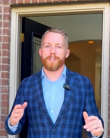 Ashton at the open front door of 1301 Coleman Dr, talking to the camera, from his listing film